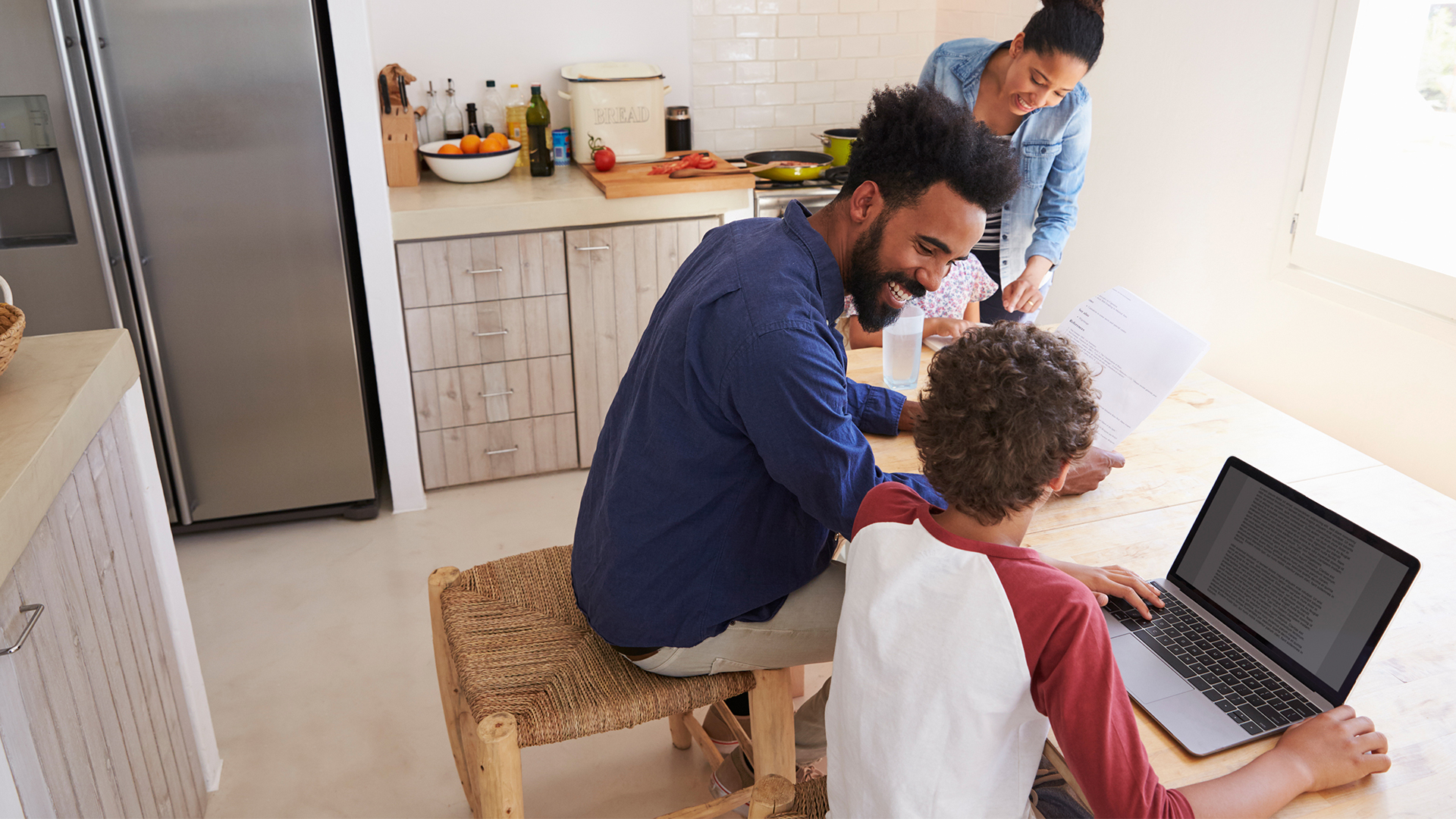 A woman, man and two children sitting at a table looking at a computer screen.