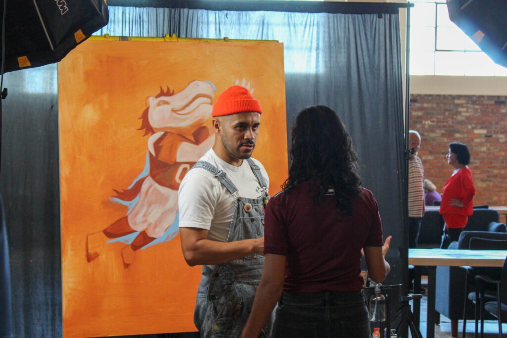 An artist painting Miles, the Denver Broncos mascot, at the Boys & Girls Clubs of Weld County's Teen Center grand opening event.